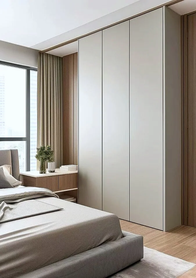 Pale full-height wardrobe beside a low window cabinet in a softly toned bedroom